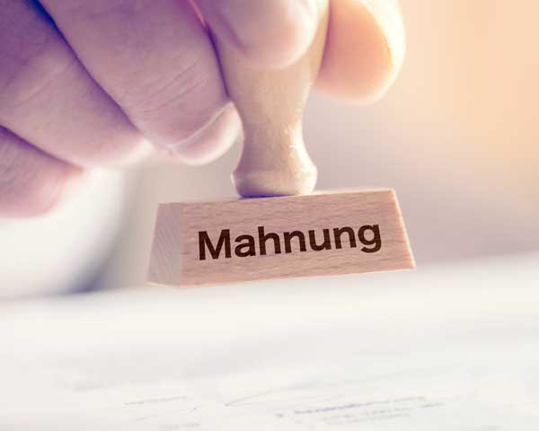 Startseite 14 Ein Mann und ein Stempel mit dem Aufdruck Mahnung – Arbeitgeberverband private Pflegeeinrichtungen – bad e.V.